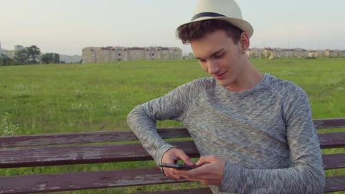 Young Adult Using Smartphone on Park Bench