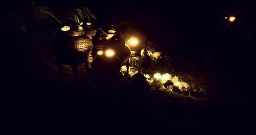 Candles Illuminate Traditional Containers in a Dark Outdoor Setting at Night