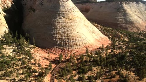 Drone footage of an unusual rock formation, from top to bottom, with indiscernible vehicles moving a