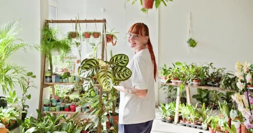 Woman Holding Plant Surrounded By Indoor Plants