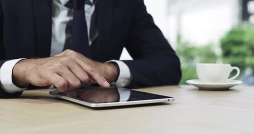 4k video footage of an unrecognizable businessman using his tablet while sitting in the office