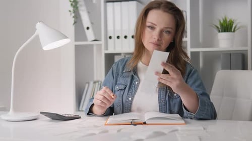 A Housewife Counts Income and Expenses at Home Home Accounting at a Table with Invoices and a