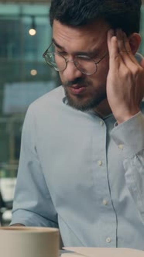 Stressed Man Massaging Temples in Office
