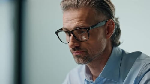 Thoughtful businessman typing laptop keyboard at empty modern office workplace