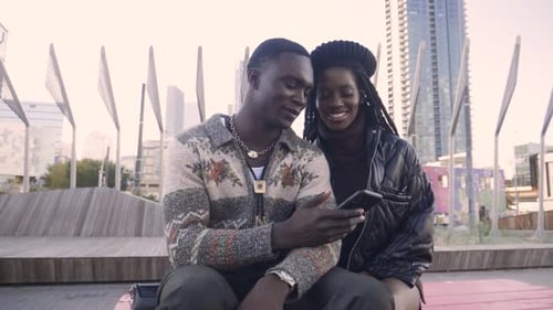 Smiling Young Couple Using Smart Phone in City Park 1819 Years