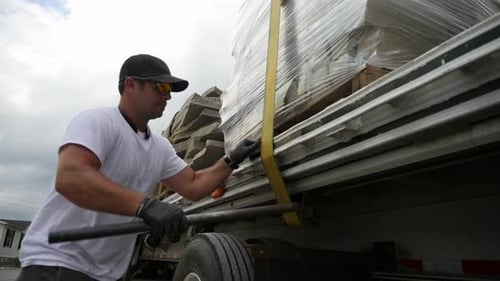 Man Tightening Straps on Flatbed Trailer