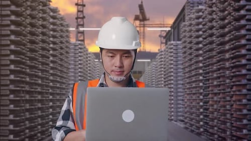 Un hombre asiático usa una computadora mientras camina en Aluminum Stock