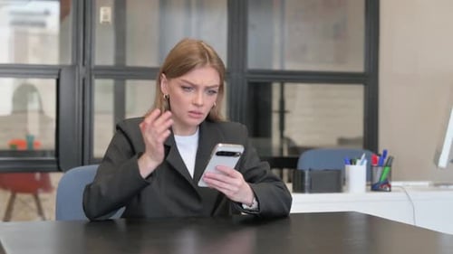 Young Businesswoman Shocked by Loss on Phone in Office