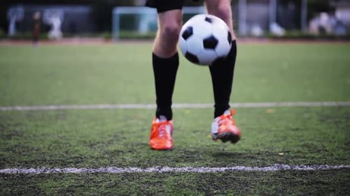 Soccer player skillfully juggling a football on the grass field during training