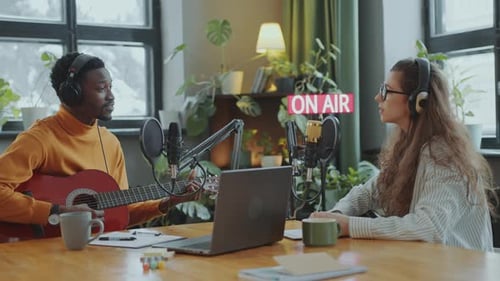 Musiker singt während der Radiosendung im Aufnahmestudio zur Gitarre