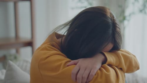 Sad Young Woman Sitting on Floor Hugging Knees