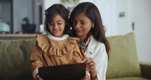 Woman and Girl Use Tablet on Couch