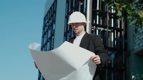 portrait of a successful handsome engineer, architect, builder, businessman in a white helmet, in a
