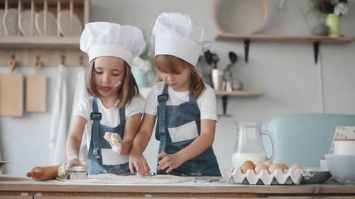 Zwei Kinder in weißer Kochuniform backen in der Küche Formen aus Teig