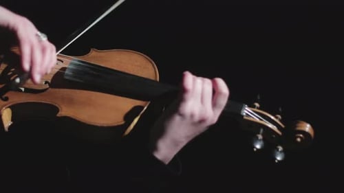 Hand Playing Violin in Dimly Lit Room