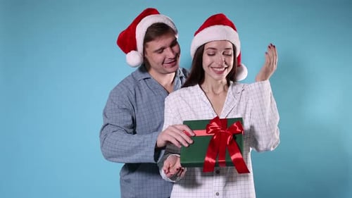 Young Couple in Pajamas Exchanging Christmas Gift