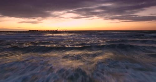 Aerial View Close To Waves at Dusk Above Ocean Beach and Pier After Sunset, Drone Shot