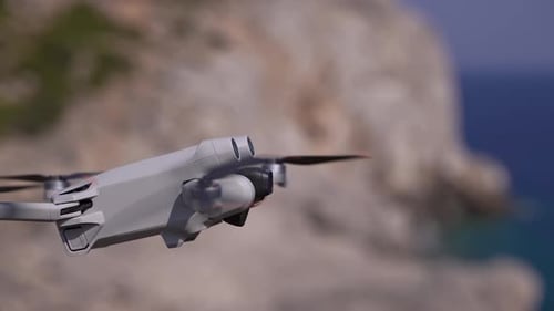 Drone Flying Near Rocky Coastline on a Sunny Day