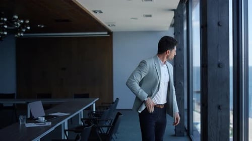 Handsome businessman looking out large office window