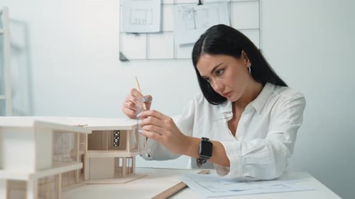 Architect using ruler to measure house model at modern office. Immaculate.