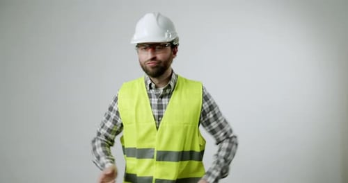 Un ouvrier du bâtiment danse avec joie avec un casque de sécurité et un gilet de sécurité