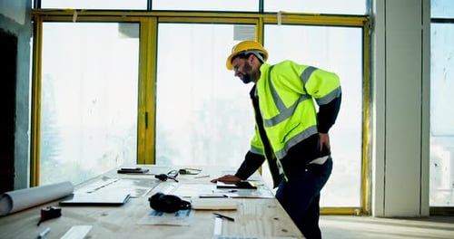 Architect, construction worker and back pain with drawing, plans and blueprints for maintenance