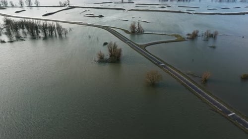 Aerial dolly forward view of a road surrounded by flooded fields along the Waal River in the Netherl