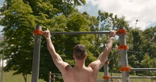 Junger Mann macht Klimmzüge an einer Bar im Park