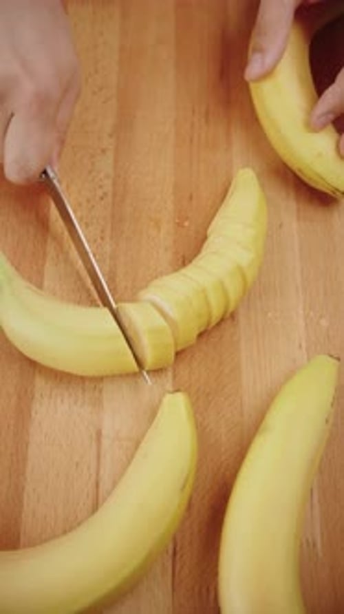 Banana Being Sliced on a Wooden Cutting Board