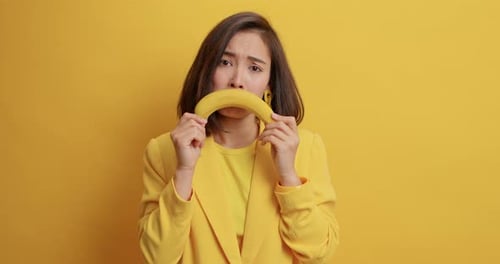 Woman Posing with Banana Smile Against Yellow Backdrop
