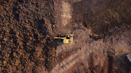 Aerial view of a wheel loader excavator with a backhoe loading sand into a heavy earthmover