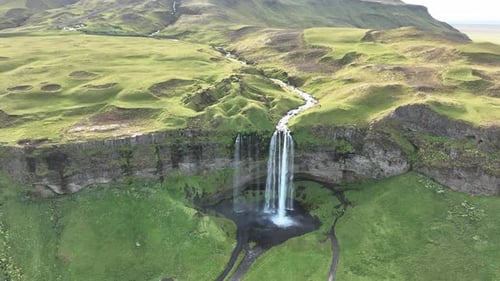 Majestic Waterfall Flowing Down Lush Green Cliff Face in Iceland Scenery
