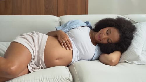Pregnant Woman Relaxing on Couch Rubbing Belly