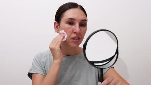 millennial young woman is doing at home facial procedure, remove makeup