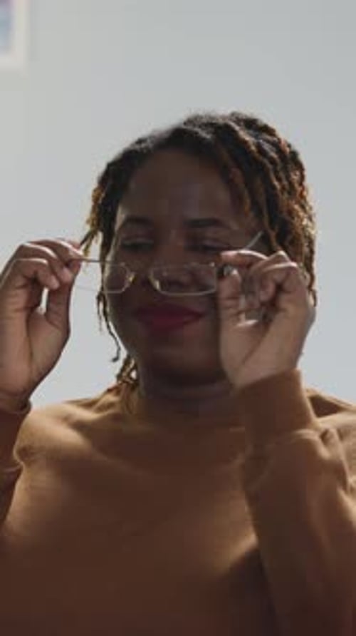 Happy Woman Smiles and Removes Glasses Indoors