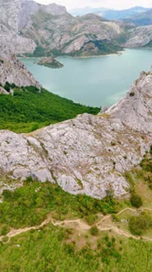 Grey bare rocks surround the beautiful lake. Drone footage approaching the rock