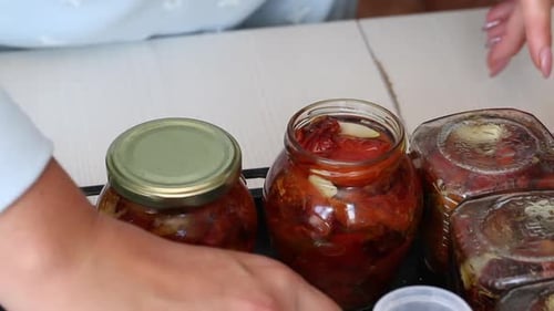 Woman Sealing Jars of Preserved Red Tomatoes