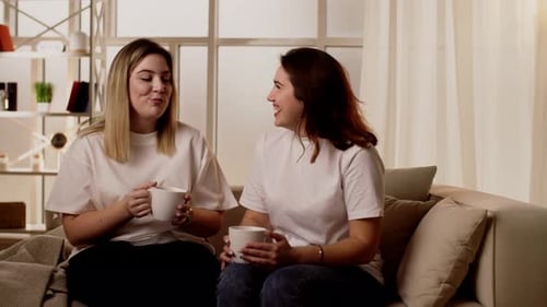 Junge Mädchen plaudern über lustige Dinge, Klatsch und Lachen auf der Couch in der Wohnung