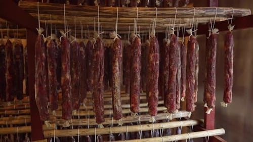 Cured Sausages Hanging Indoors on Wooden Frame