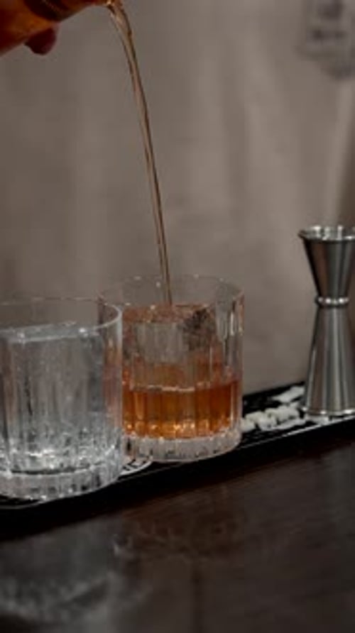 Bartender Pouring Cocktail into Glass with Ice