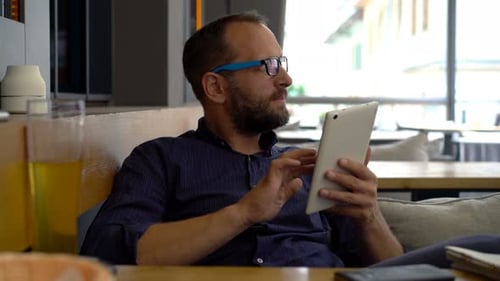 Young Handsome Man with Tablet Computer Sitting in Cafe 30s