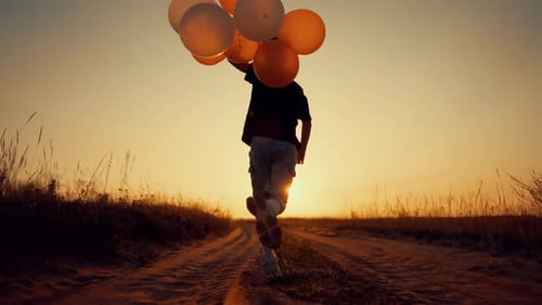 Boy Runs With Balloons Along Rural Path at Sunset