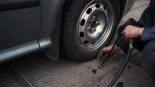 Man Adding Air to Car Tire with Gauge