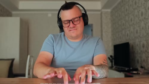 Man with Headphones Pretends to Type at Table