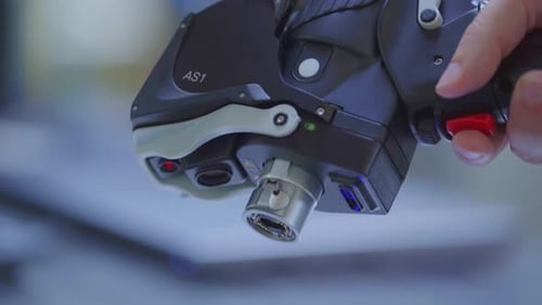 Sostenga con la mano un escáner láser futurista y presione el botón rojo. Mida piezas en 3D, de cerca.