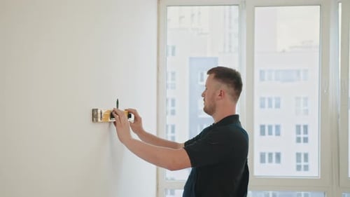 Construction Builder Working with Water Level Tool to Do Measurement Using Bench