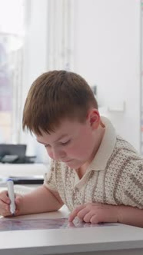 Young Boy Drawing at a Table in a Bright Indoor Learning Space