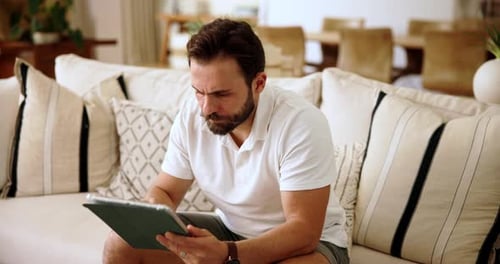 Man Using Tablet Relaxing on Couch at Home