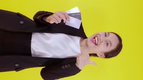 Smiling Woman Holds Credit Cards on Yellow Background