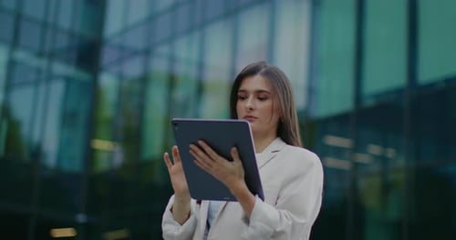 Beautiful Caucasian Woman Standing Outside Her Office Building and Using Tablet Device Typing on